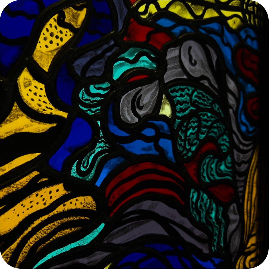 Close-up of a colorful stained glass window with abstract patterns in yellow, blue, red, and green.