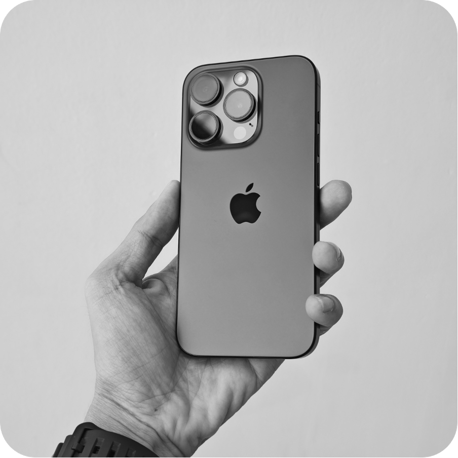 A hand holding a black and white iPhone 14 Pro with the Apple logo visible on the back of the phone.